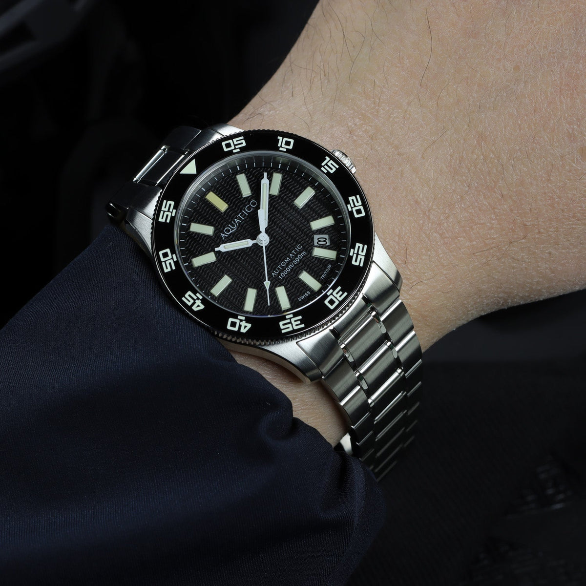 Aquatico Sea Sentinel black dial watch worn on a wrist with a steel bracelet