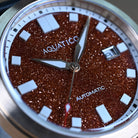 Red aventurine automatic watch photographed in warm light to highlight its elegant texture and depth.